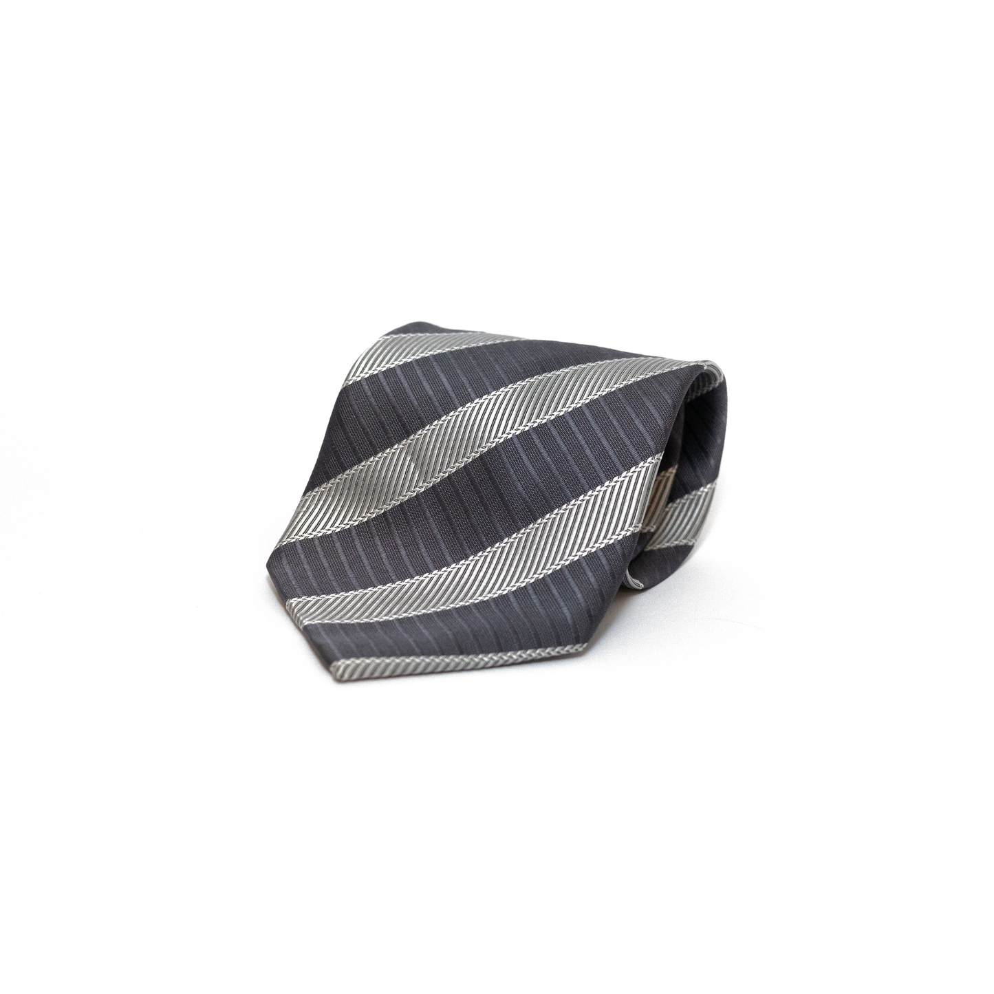 Grått vintage slips fra italienske Ermenegildo Zegna, med diagonale striper i mørkere grått og sølvtone. Den vevde strukturen gir slipset variasjon i overflaten, samtidig som det holder seg innenfor et klassisk og dempet uttrykk.