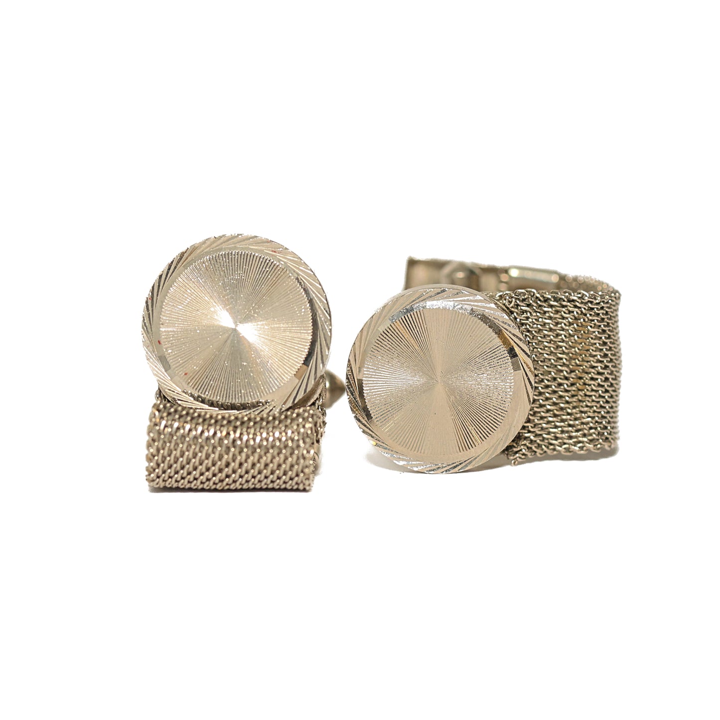 Klassiske vintage mansjettknapper fra 60-tallet med rund front i sølvtone, dekorert med et fint gravert solstrålemønster som fanger lyset i ulike vinkler. En fleksibel kjedelenke i mesh vikles elegant rundt mansjetten for en behagelig passform. Et raffinert valg for mannen som verdsetter det understatede og veldreide.