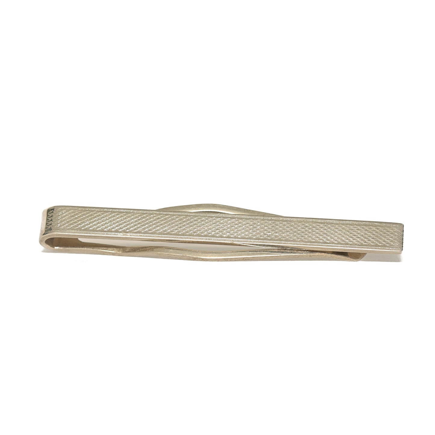 Vintage slipsnål fra 60-tallet i avlang form og sølvtone, dekorert med et fint hakket rutemønster som dekker hele lengden. Den tette teksturen fanger lyset i et dempet, men levende spill og gir slipsnålen et raffinert preg uten å bli prangende. Et tidløst valg for mannen som setter pris på diskrete detaljer og klassisk håndverk.