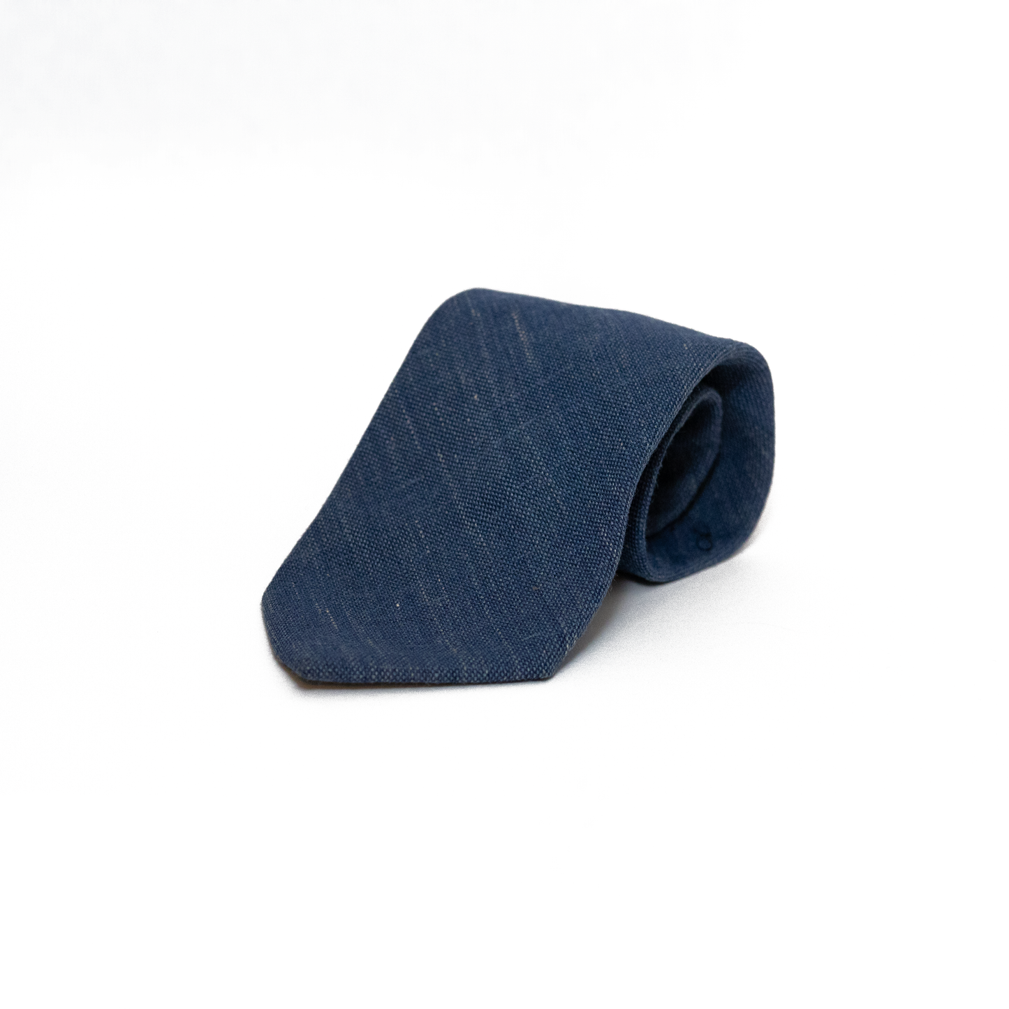 Mørkeblått vintage slips fra Brian Lynch, vevd i en grovere struktur som gir slipset en matt overflate og en naturlig variasjon i fargen. Den teksturerte vevingen gir slipset karakter og dybde, samtidig som det holder seg innenfor et klassisk og dempet uttrykk.