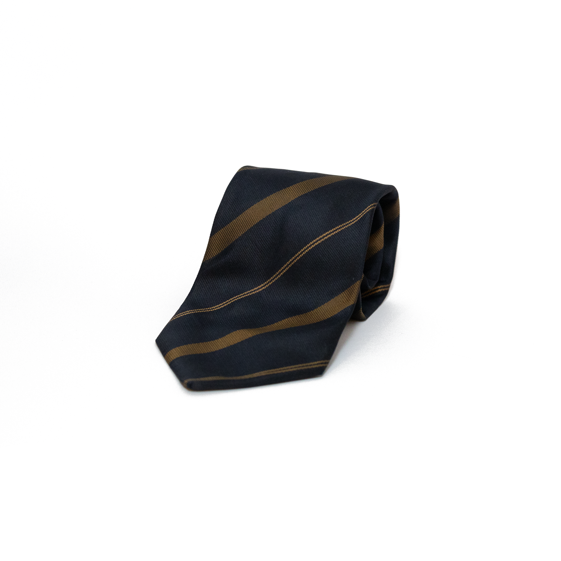 Mørkeblått vintage slips fra Mlewin & Sons, med diagonale striper i olivengrønt og en tynnere stripe i gulltone. Det klassiske stripemønsteret gir slipset et tradisjonelt regimentalt uttrykk, samtidig som det holder seg innenfor et dempet og tidløst utseende.