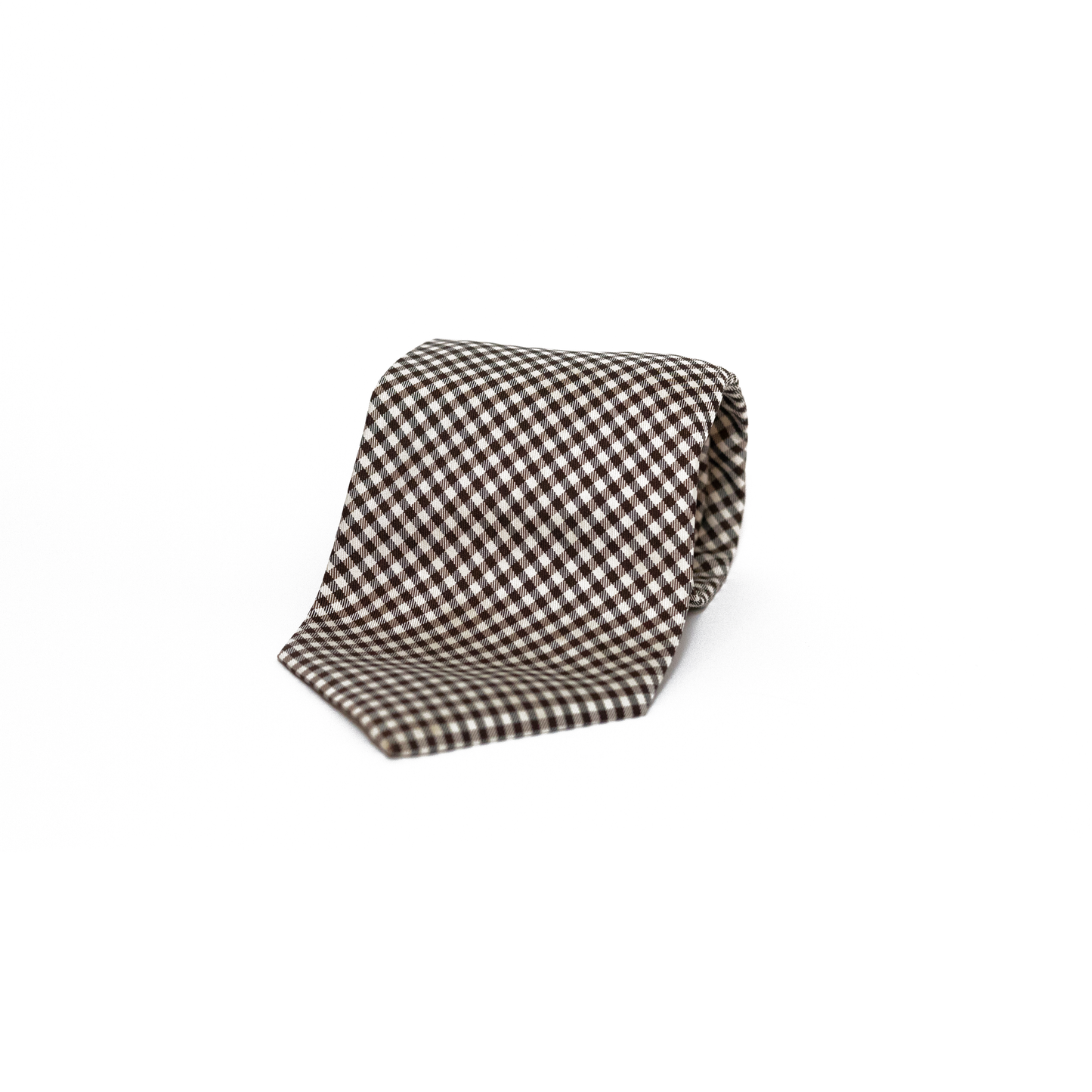 Vintage silkeslips fra West Point i et klassisk gingham-mønster, vevet i brunt og hvitt over hele lengden. Det rutete mønsteret gir slipset et leken og samtidig stilsikkert preg, og de varme jordtonene gjør det til en fin følgesvenn til både tweed og lin.
