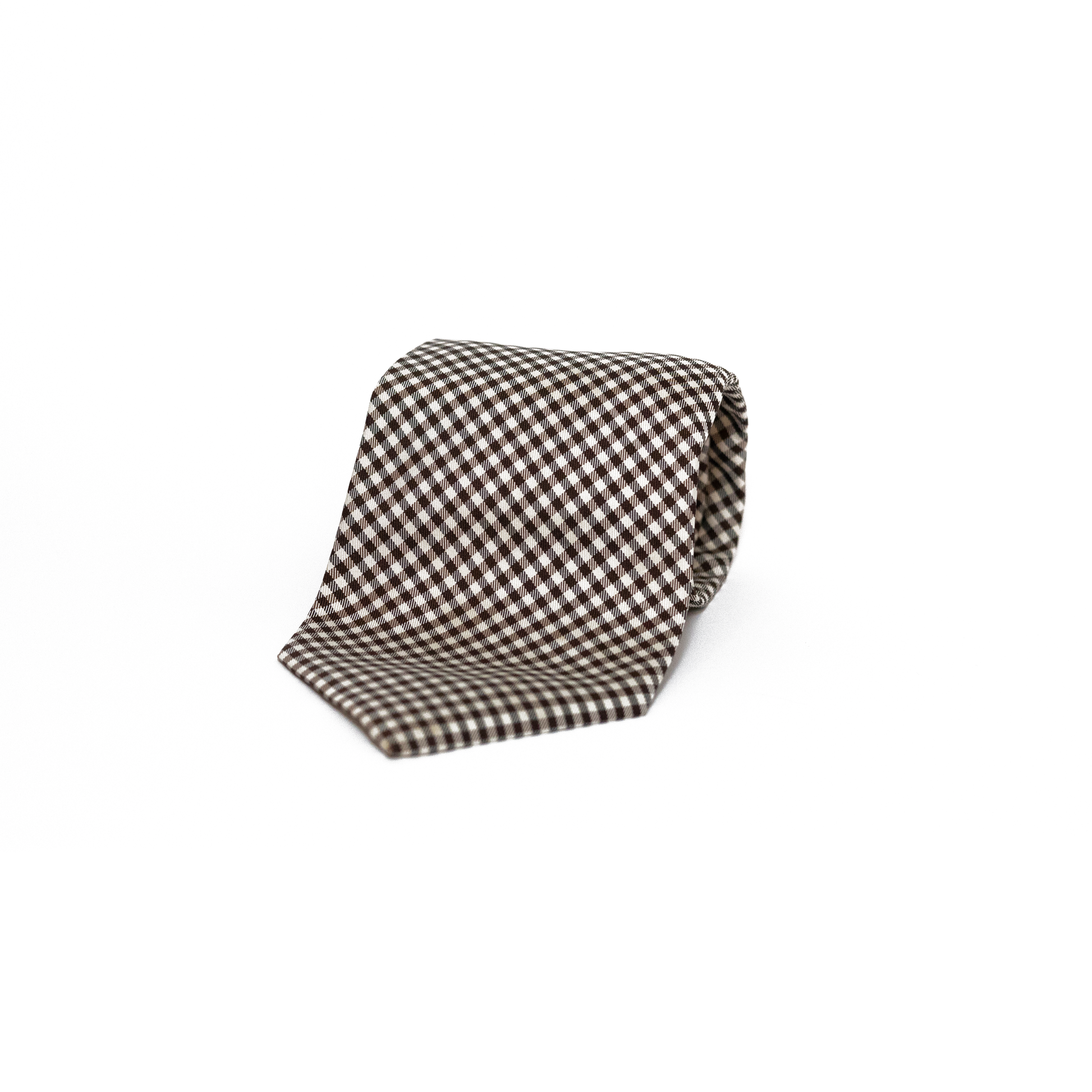Vintage silkeslips fra West Point i et klassisk gingham-mønster, vevet i brunt og hvitt over hele lengden. Det rutete mønsteret gir slipset et leken og samtidig stilsikkert preg, og de varme jordtonene gjør det til en fin følgesvenn til både tweed og lin.
