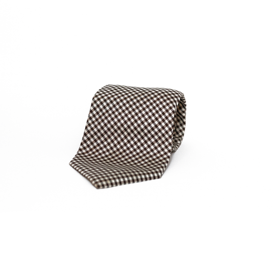 Vintage silkeslips fra West Point i et klassisk gingham-mønster, vevet i brunt og hvitt over hele lengden. Det rutete mønsteret gir slipset et leken og samtidig stilsikkert preg, og de varme jordtonene gjør det til en fin følgesvenn til både tweed og lin.